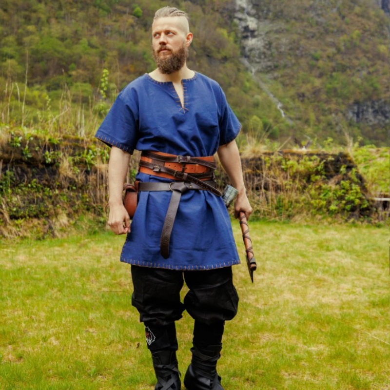 Un viking porte une tunique bleu roi avec une ceinture large en cuir marron