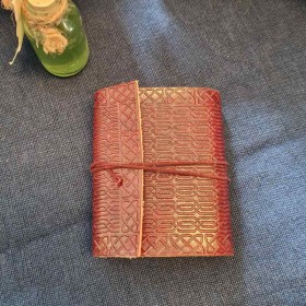 Le petit carnet à la couverture en cuir gaufrée se ferme avec un cordon.