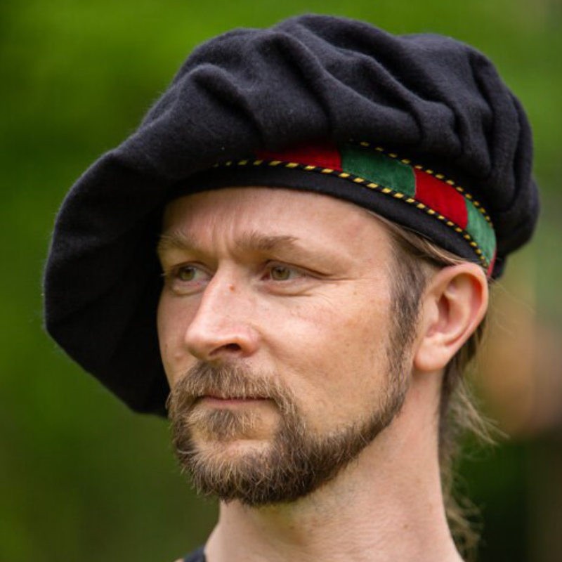 Le béret de ménestrel avec la bordure en velours rouge et verte