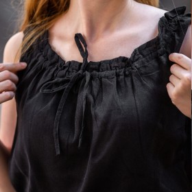 Ici les bretelles du chemisier noir sans manches sont relevées